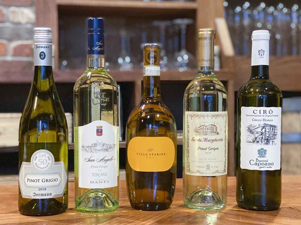 5 bottles of various white wines on wood table